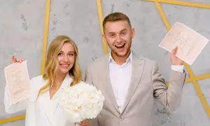 Szczęśliwa para młoda trzyma dokumenty. Czy bierzmowanie jest potrzebne do ślubu? To pytanie nie dotyczy tej radosnej chwili.