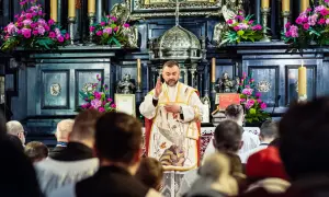 Ksiądz odprawia mszę gregoriańską. Kiedy zamawiać? W kościele, wśród wiernych, przy ołtarzu ozdobionym kwiatami i świecami.