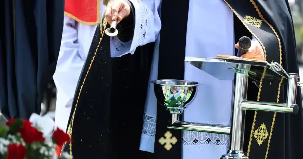 Osoba w szatach liturgicznych sypie ziarna. Czy to apostata, kto to? Ceremonia z mikrofonem i kielichem.